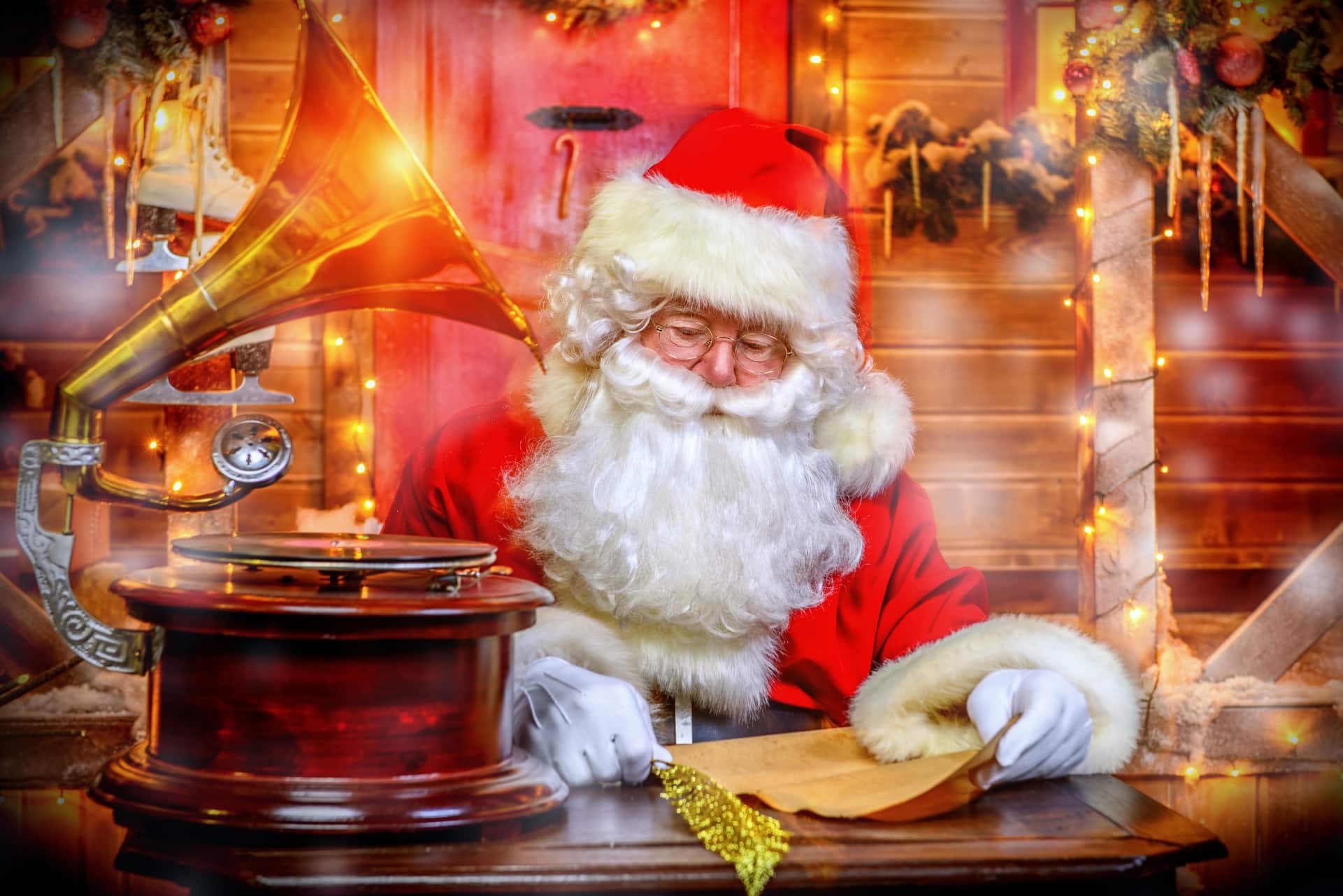 Babbo Natale con occhiali sorride accanto a un grammofono dorato in un ambiente natalizio illuminato