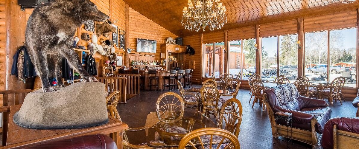 Lussuosa hall di caccia con animale impalato, lampadario cristallo, arredi vintage e ampie finestre panoramiche sulla natura